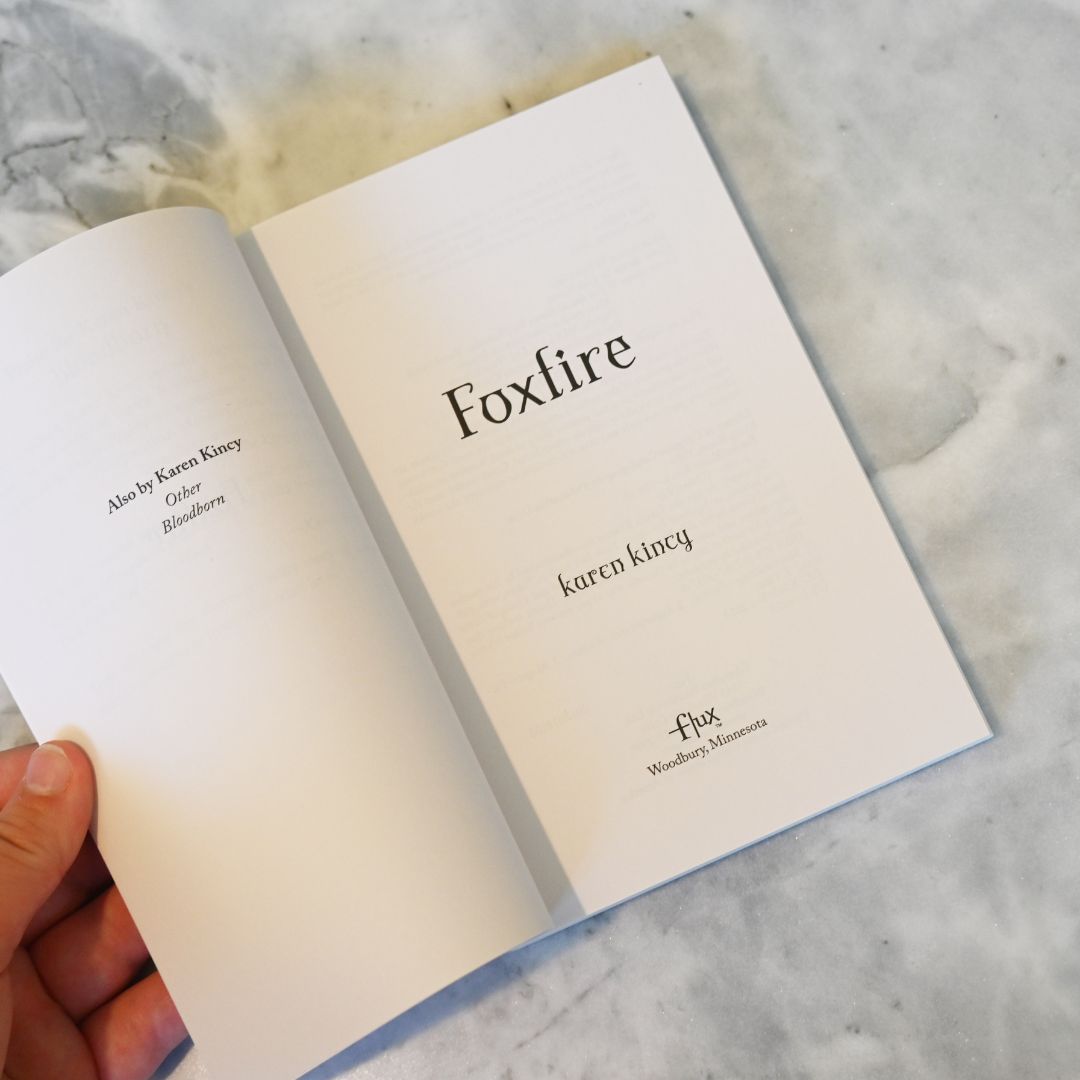 Open book titled 'Foxfire' by Karen Kincy on a marble surface