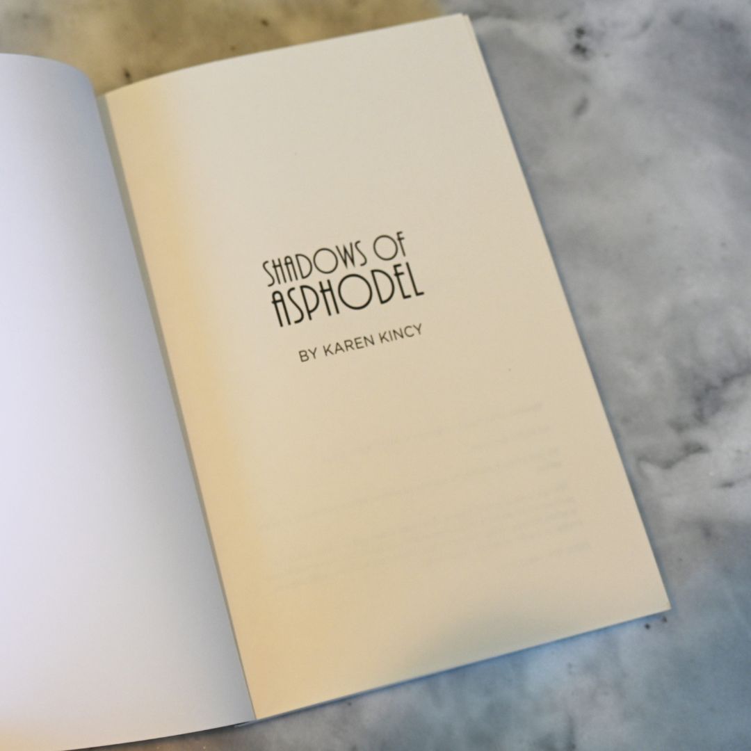 Open book with 'Shadows of Asphodel' by Karen Kincy on a marble surface
